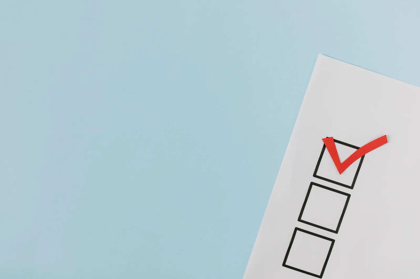 A checklist with a red checkmark symbolizing a completed task on a pastel blue background. Common legal email marketing questions: a framework