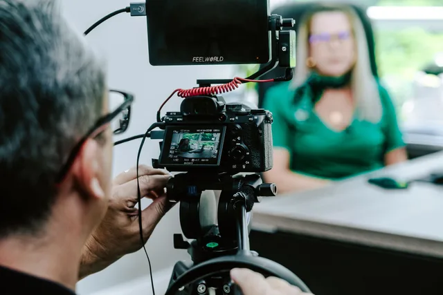 Close-up of a videographer filming a woman in an office setting, highlighting professional equipment. Nine law firm social media formats worth adapting this quarter
