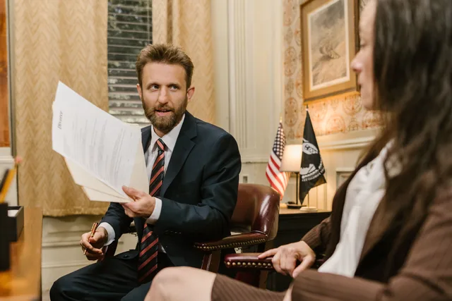 Lawyer in suit discussing documents with client in an office setting. New York City legal SEO costs compared with Los Angeles and Chicago