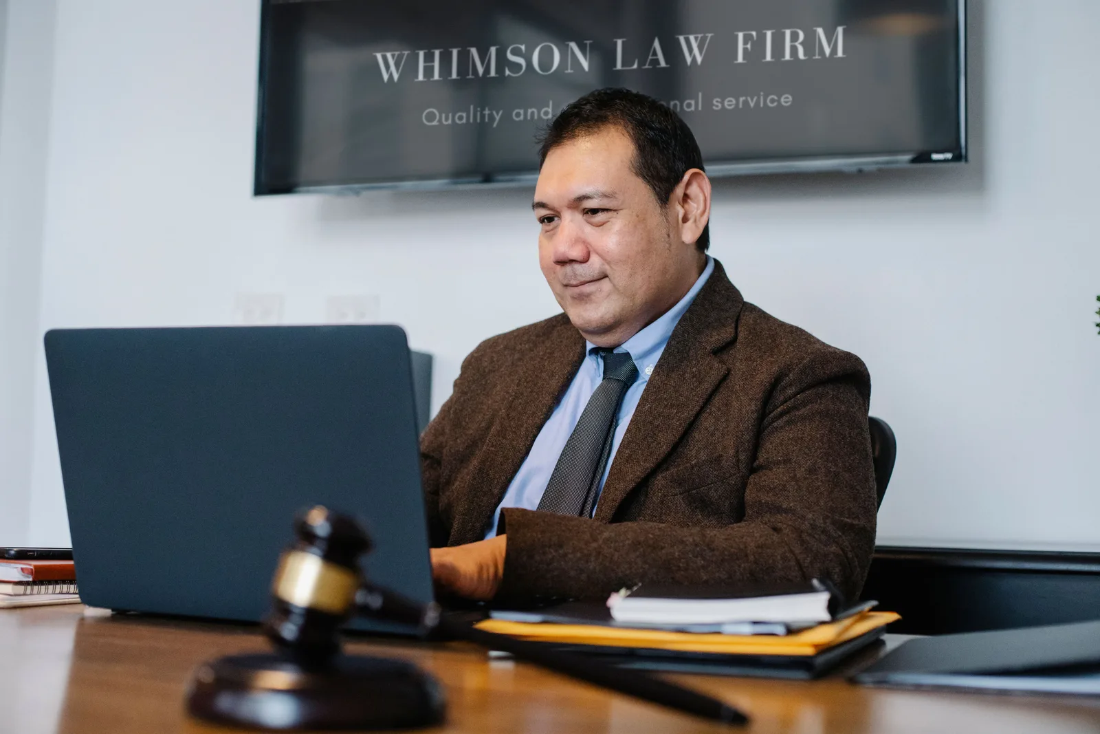 Experienced middle aged ethnic happy male working with netbook at table with judge hammer. What federal court data from PACER can do for a US law firm blog?